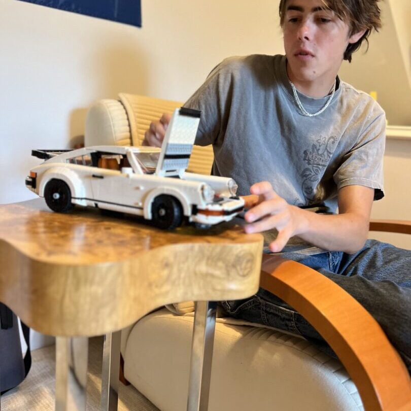 A young man next to a LEGO 10295 Creator Porsche 911